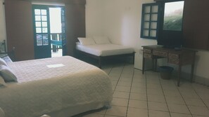 A hotel room with a bed, a chair, a desk, and a television. - Casa Amor do Mar (Búzios)