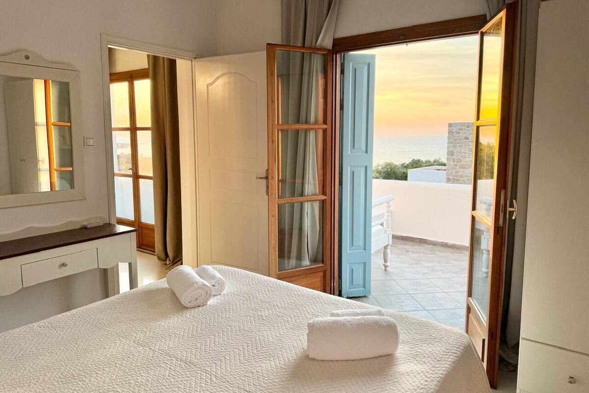Una habitación de hotel con cama, baño y vista al mar.