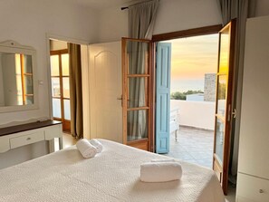 A hotel room with a bed, a bathroom, and a view of the sea.