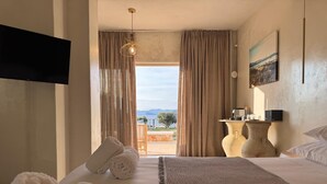 Une chambre d’hôtel avec un lit, des serviettes, une télévision, une table avec une lampe et une vue sur l’extérieur.