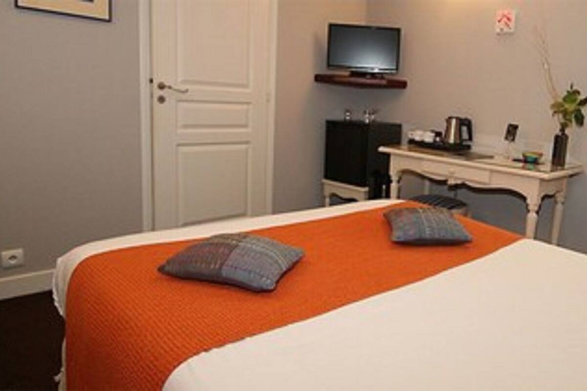 Una habitación de hotel con cama, escritorio y televisión, además de una ventana.