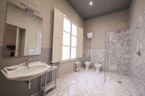 Une salle de bain avec un lavabo, deux toilettes, une douche et un grand miroir.