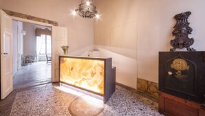 A reception area with a marble counter, a chandelier, and a decorative wooden panel.