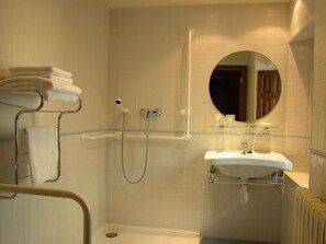Een badkamer met douche, wastafel en spiegel.