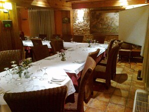 A dining area with long tables set for a meal, surrounded by wicker chairs.