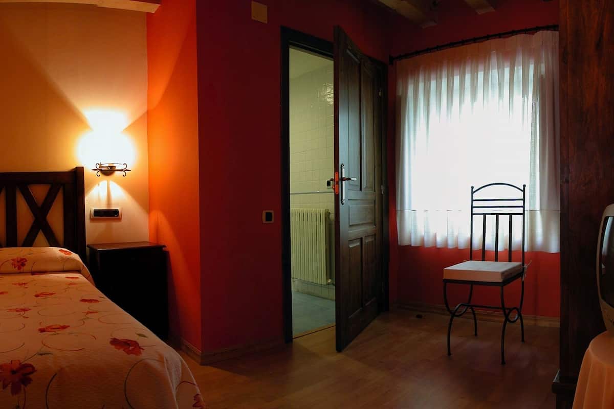 Ein Zimmer mit einem Bett, zwei Nachttischlampen, einem Sessel und einem Fernseher.