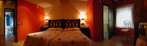 Een kamer met een bed, twee bedlampjes, een stoel en een televisie.