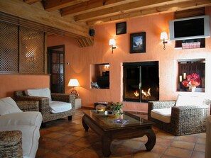 A cozy living room with wicker furniture, a fireplace, and wall-mounted lighting.