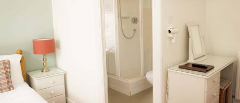 A bedroom with a bed, nightstand, dresser, and a shower stall.