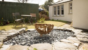 A garden with a decorative metal bowl, stone pathway, and a wooden fence. - The Royal Oak Hotel (Buckie)