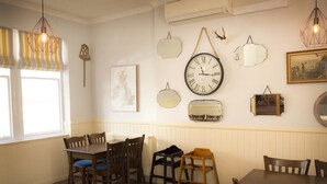A dining area with a wooden table and chairs, a wall-mounted clock, and various wall decorations. - The Royal Oak Hotel (Buckie)