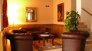 A living room with a brown leather sofa, two leather armchairs, a coffee table, and a large potted plant. - La Quiete Resort (Romeno)