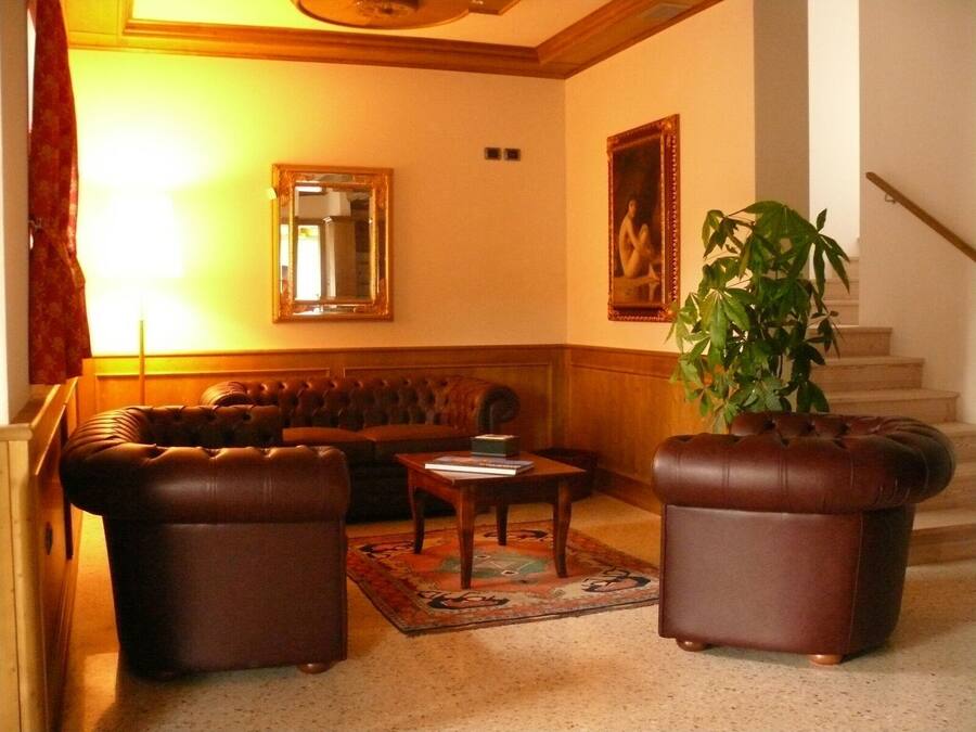 A living room with a brown leather sofa, two leather armchairs, a coffee table, and a large potted plant.