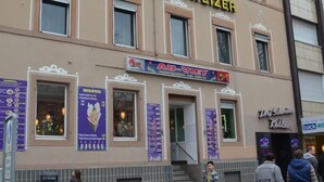 Un hotel llamado "HOTEL DREI SCHWEIZER" con un letrero, una escalera que lleva a la entrada y algunas personas caminando.