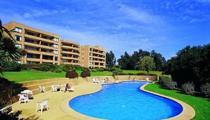 Een hotel met een zwembad, terras en een verzorgd gazon.