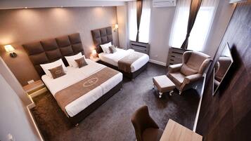 A hotel room with two beds, a sofa, a TV, and a desk.