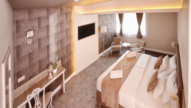 Hotelkamer met een groot bed, een bureau, een stoel, een flatscreen televisie en een raam met gordijnen.