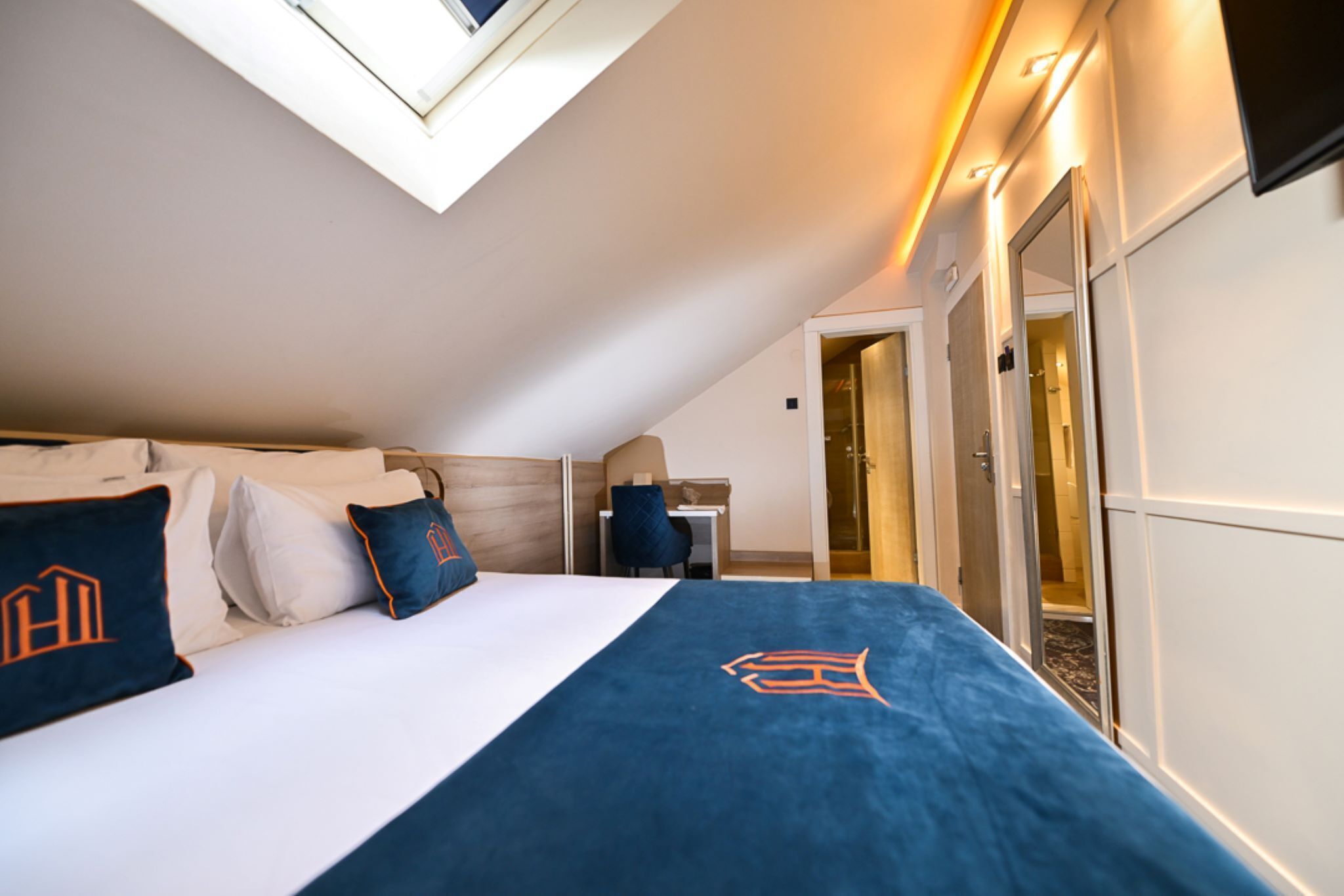 A hotel room with a bed, a desk, a chair, and a large window.