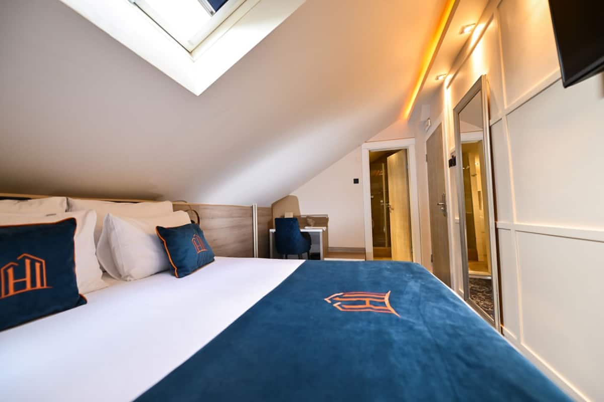 A hotel room with a bed, a desk, a chair, and a large window.