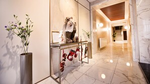 Een moderne lobby met een marmeren vloer, een glazen vitrine met kerstsokken en een decoratieve plant.