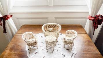 A wooden table with three wicker chairs and a lace table runner.