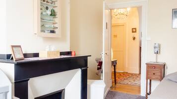 Une chambre d’hôtel avec une cheminée, un lit, un bureau et un lustre.