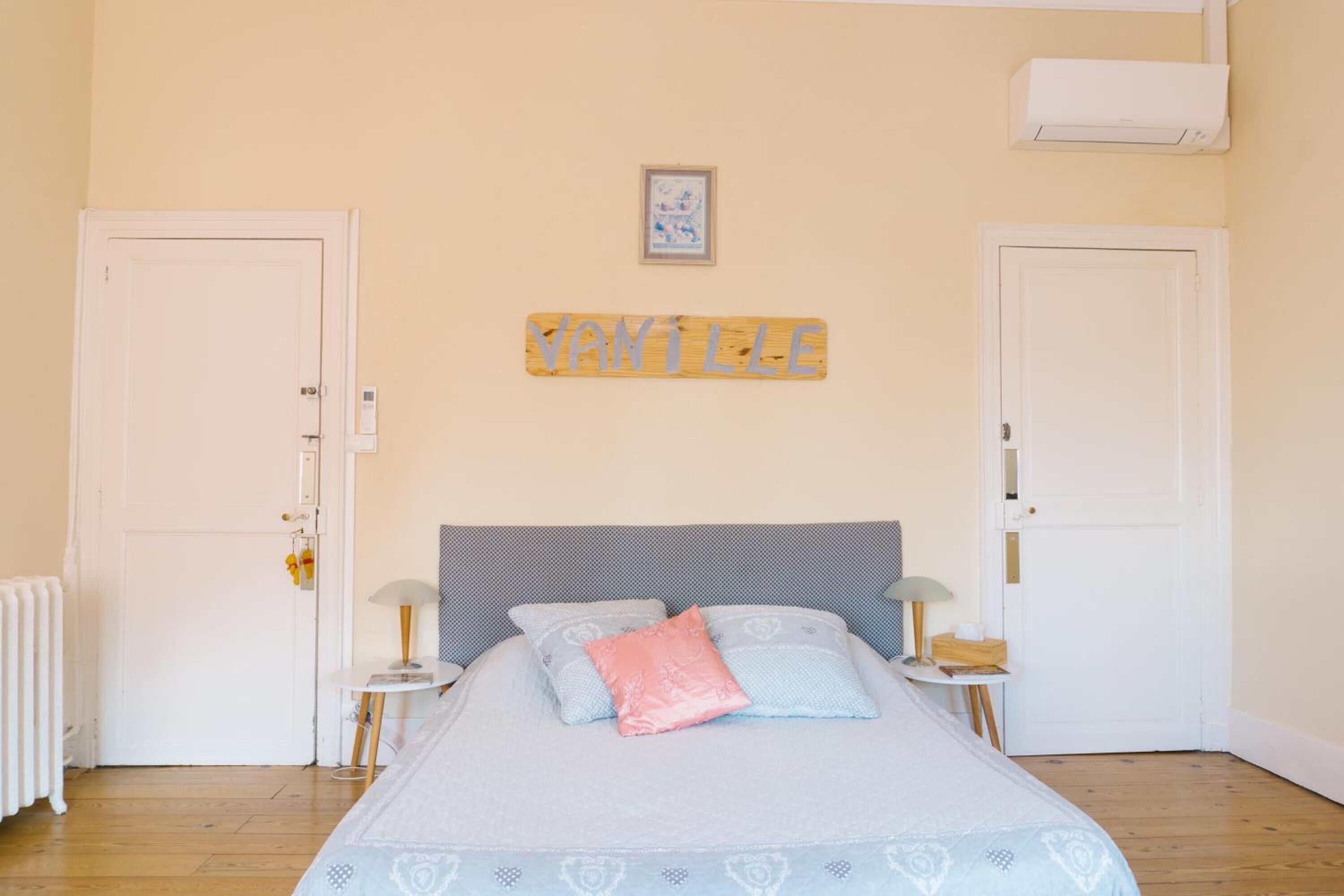 Une chambre à coucher comprenant un lit, deux tables de chevet, une commode, un radiateur et un climatiseur fixé au mur.