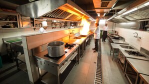 Una cocina profesional con electrodomésticos de acero inoxidable, una campana extractora grande y un chef preparando comida.