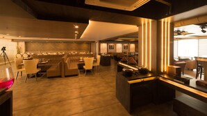 Un restaurante moderno con barra, mesas y sillas, y una cocina visible al fondo.