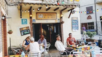 Un área con mesas y sillas para sentarse al aire libre, un letrero que dice 'LA CUINETA DE CAL. TRUIET', y una señalización de estacionamiento con la letra 'P'.