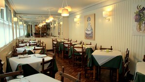 A restaurant with multiple tables, chairs, and a long counter. - Hostal Pachin (Mieres)