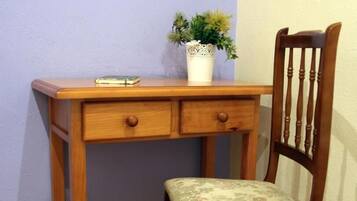 A wooden desk with two drawers and a chair with a floral cushion.