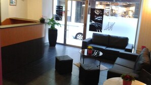 A reception area with a reception desk, a sofa, a coffee table, and a potted plant. - Hostal Pachin (Mieres)