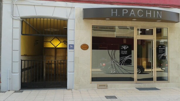 A hotel entrance with a glass door, a sign reading "H. Pachin," and a plaque indicating the year 1980. - Hostal Pachin (Mieres)