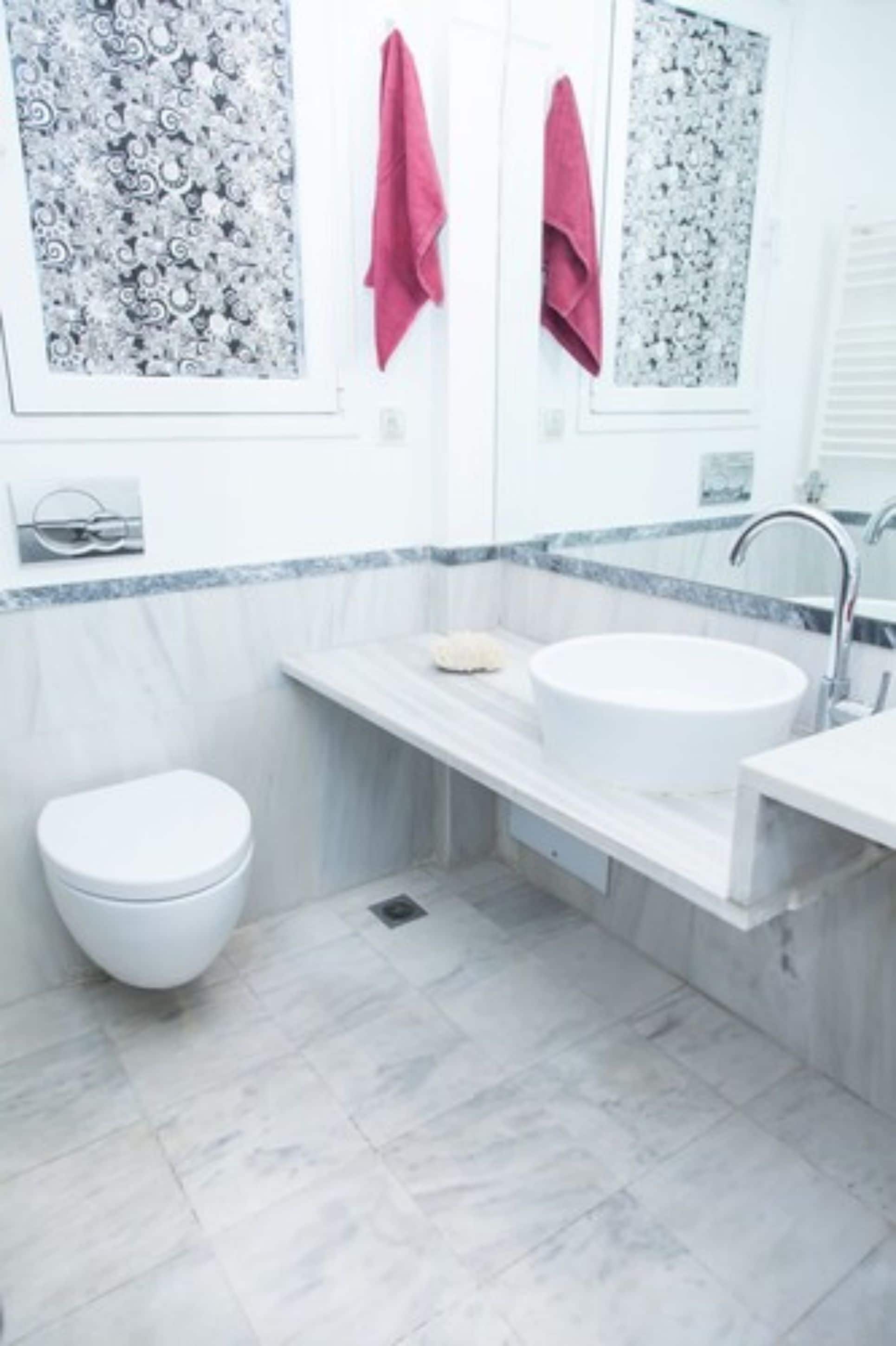 A bathroom with a white toilet, a sink with a mirror above it, and a shower area.