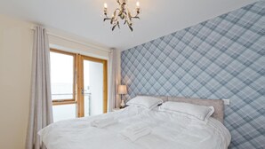 A neatly made bed with white linens, a chandelier, and a plaid-patterned wall. - Greeg Court (Dublin)