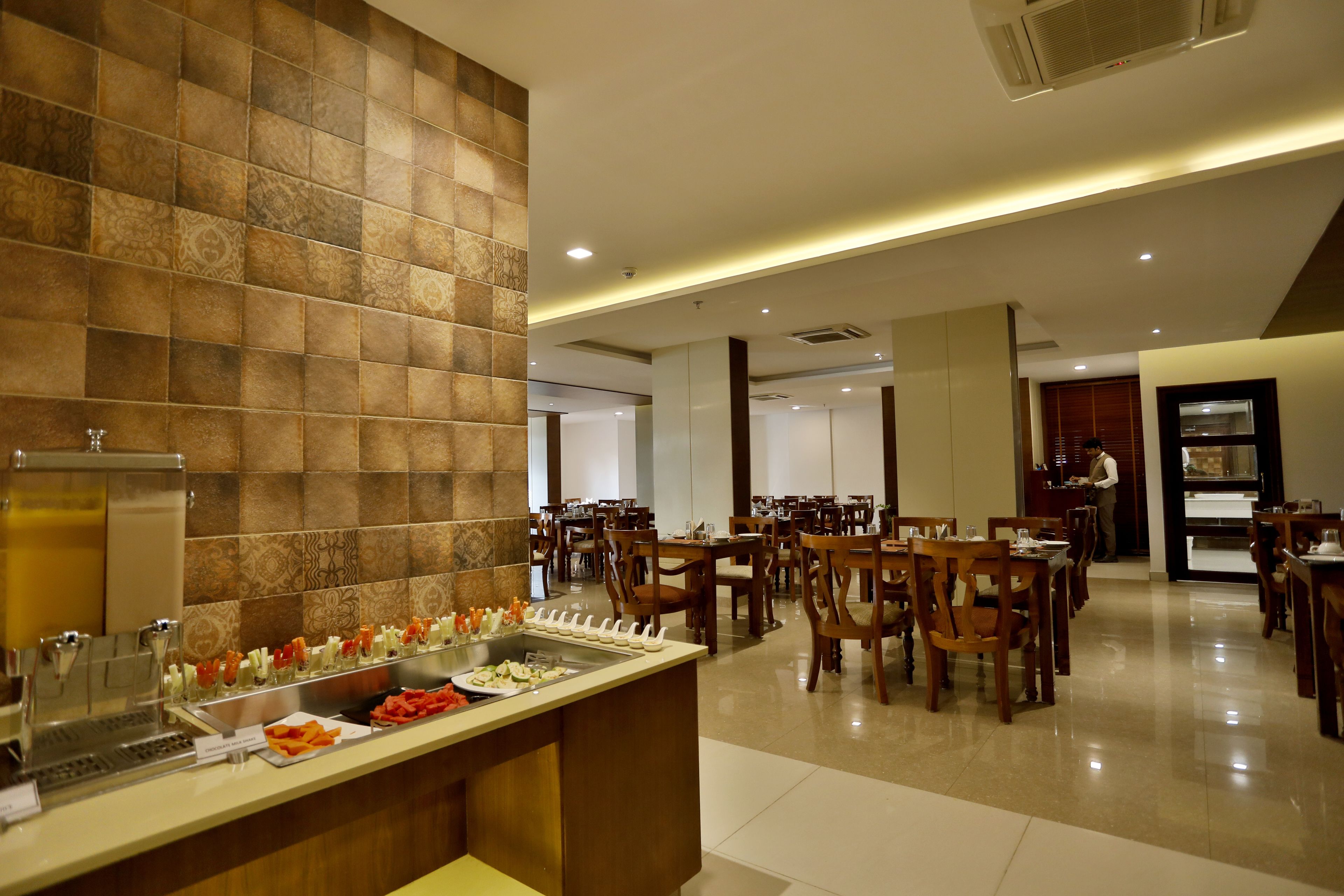 A hotel dining area with a buffet, wooden chairs, and tables.