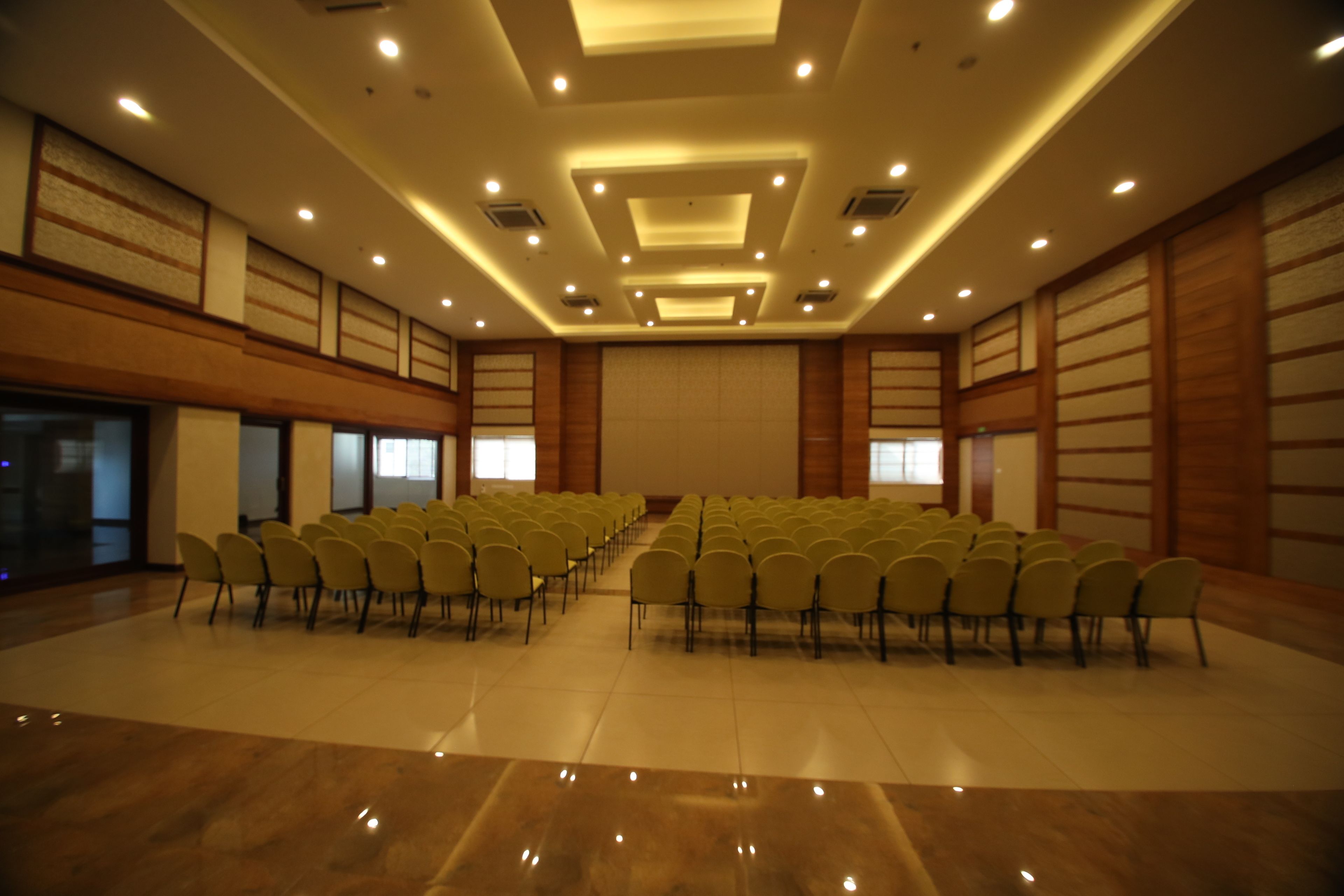 A conference room with rows of chairs, a polished floor, and recessed lighting.