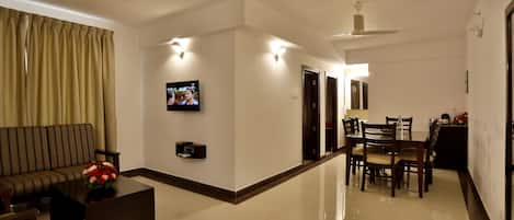 Una sala de estar moderna con sofá, mesa de centro, televisor y comedor con sillas y mesa.