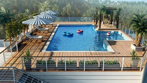 Una piscina en la azotea con terraza de madera, sillas de descanso y sombrillas.
