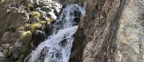Una cascata naturale in una gola rocciosa, circondata da vegetazione rigogliosa.