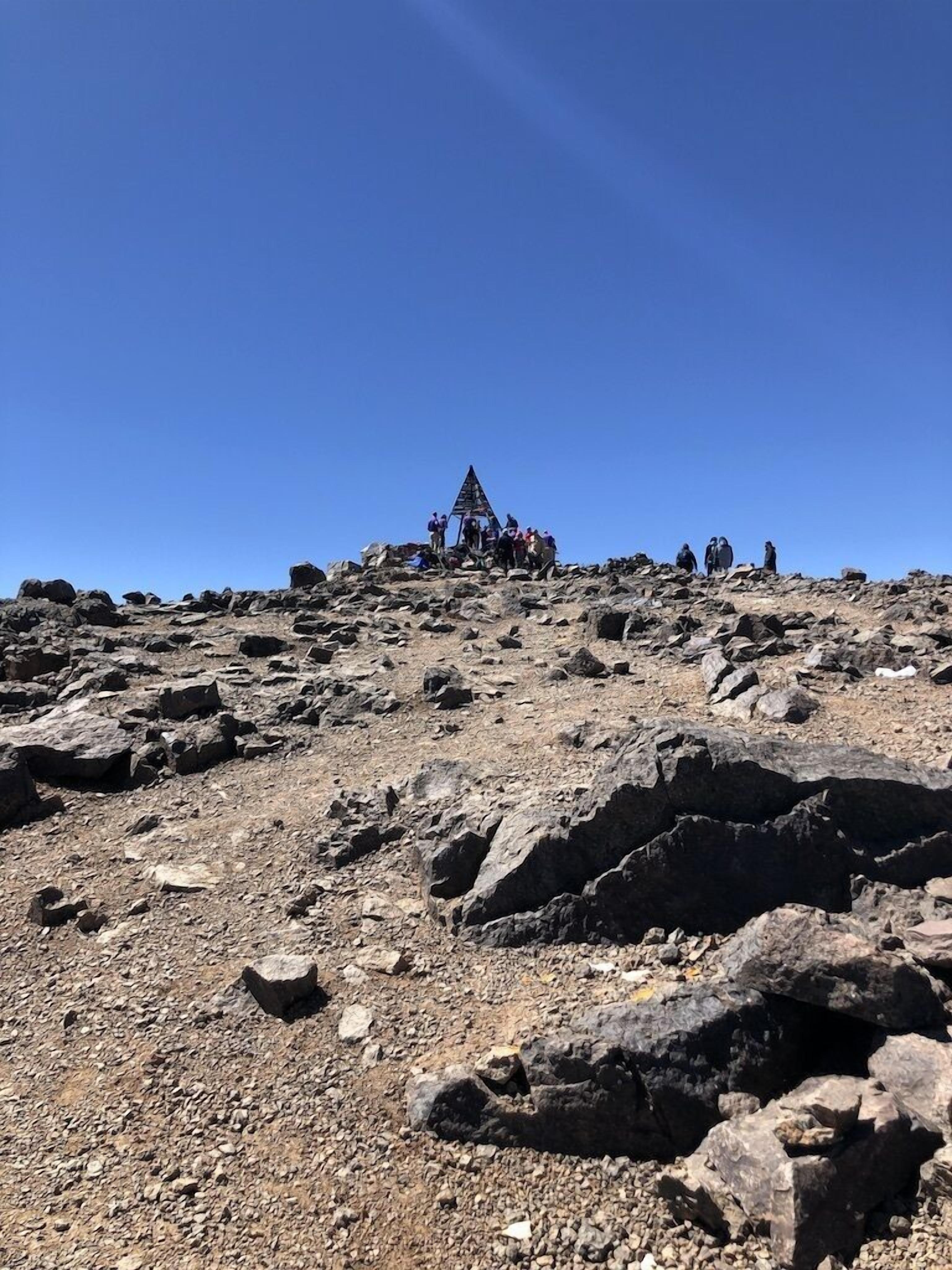 A rocky mountain peak with a pyramid-like structure at the summit.
