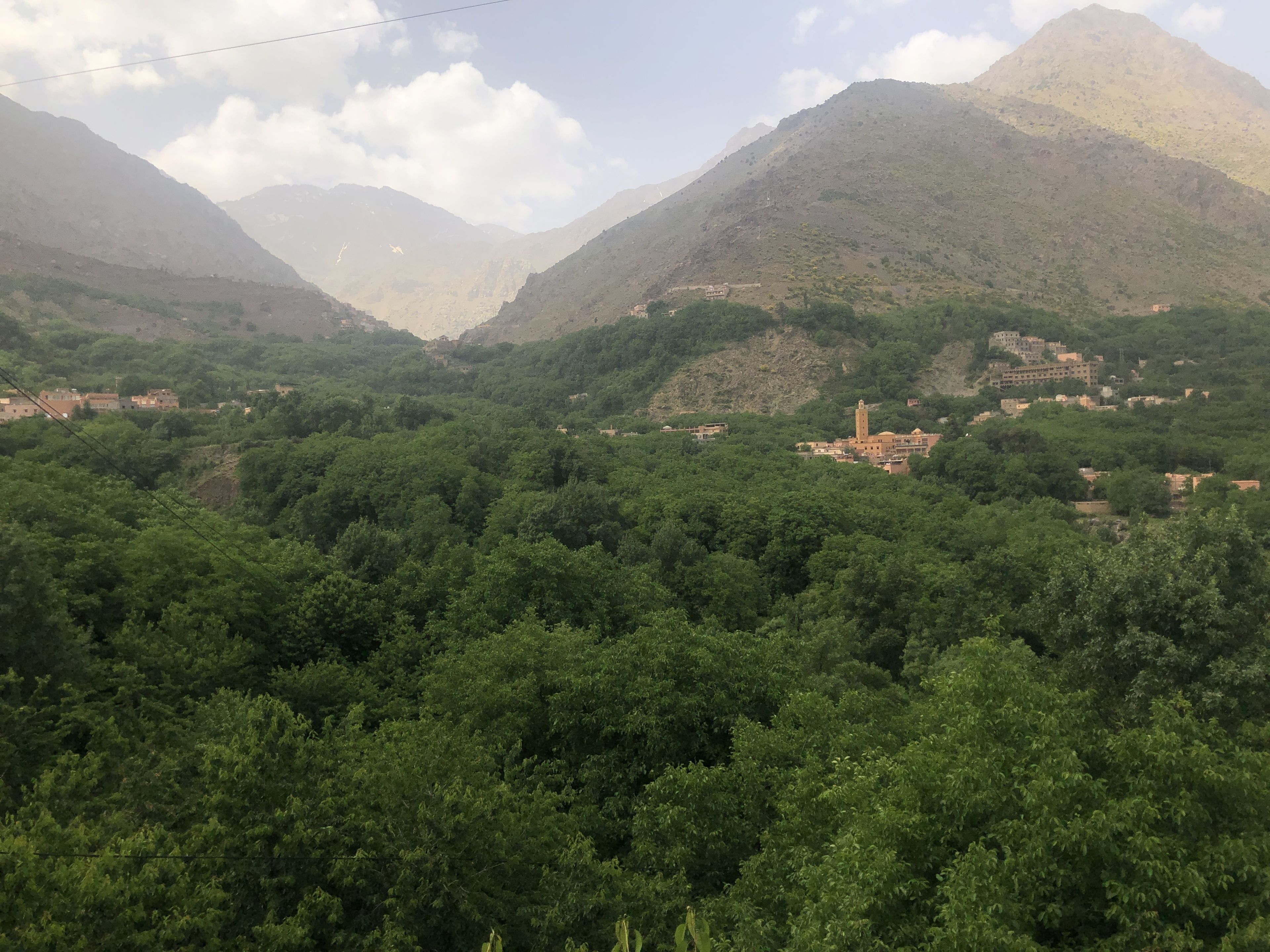 A mountainous landscape with dense green vegetation and scattered buildings.
