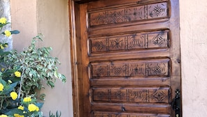 Una puerta de madera con tallas elaboradas, un tirador de metal y un felpudo.