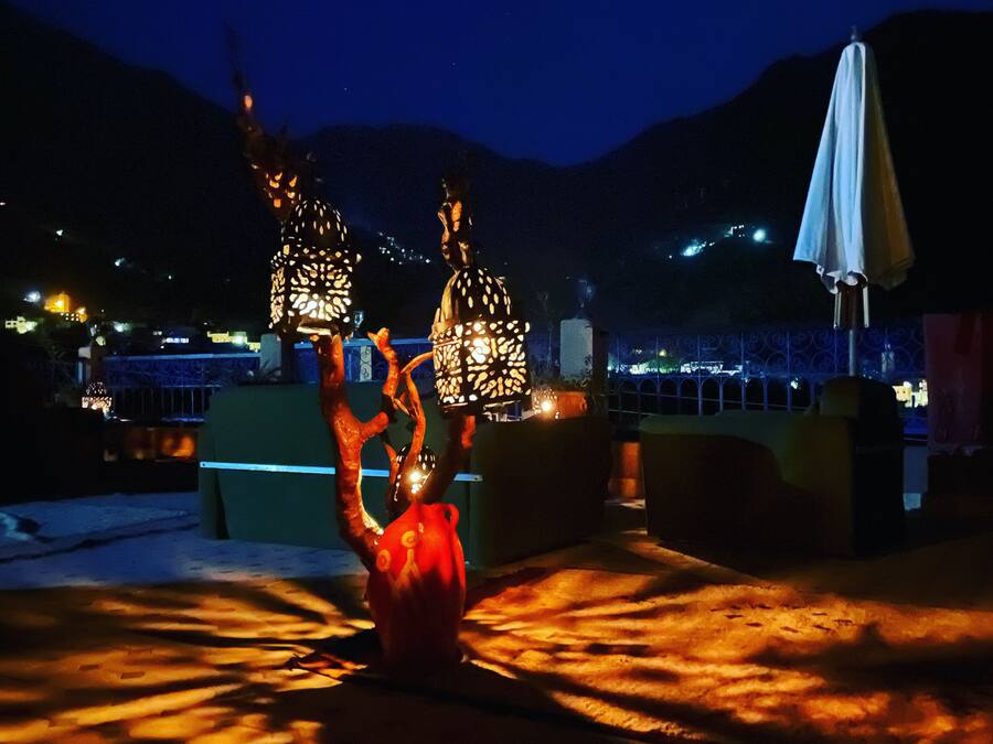 A rooftop terrace with decorative lighting and a red vase.