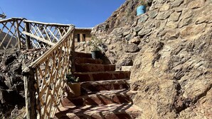 Unos escalones de piedra con barandilla de madera que ascienden por una ladera rocosa.