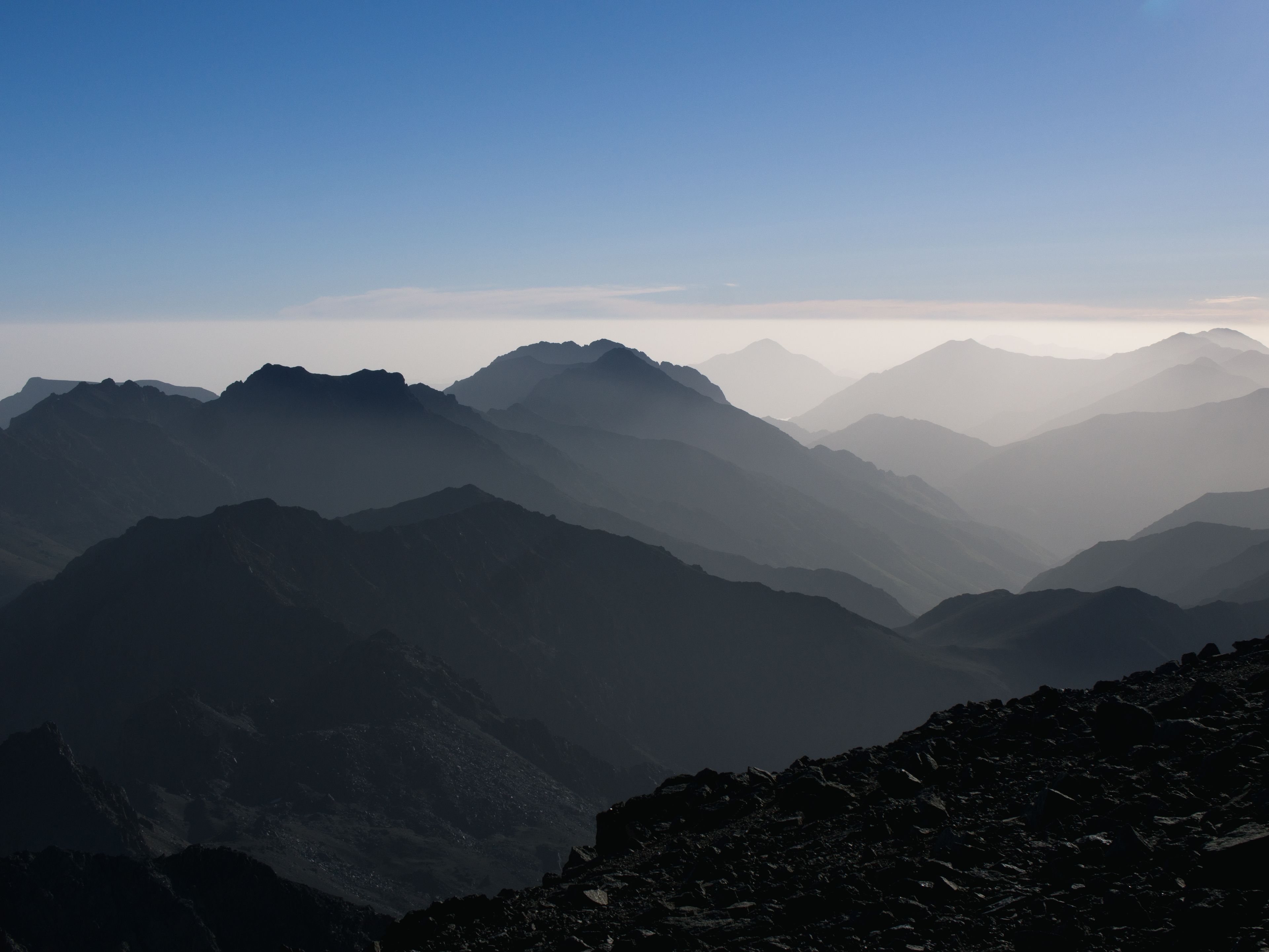 A mountainous landscape with layered peaks and a clear sky.