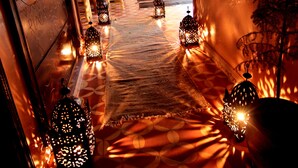 Un pasillo con alfombra estampada, faroles decorativos y una planta en maceta.