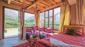 Una habitación con una cama grande, vistas a la montaña y un balcón con mesa y sillas.