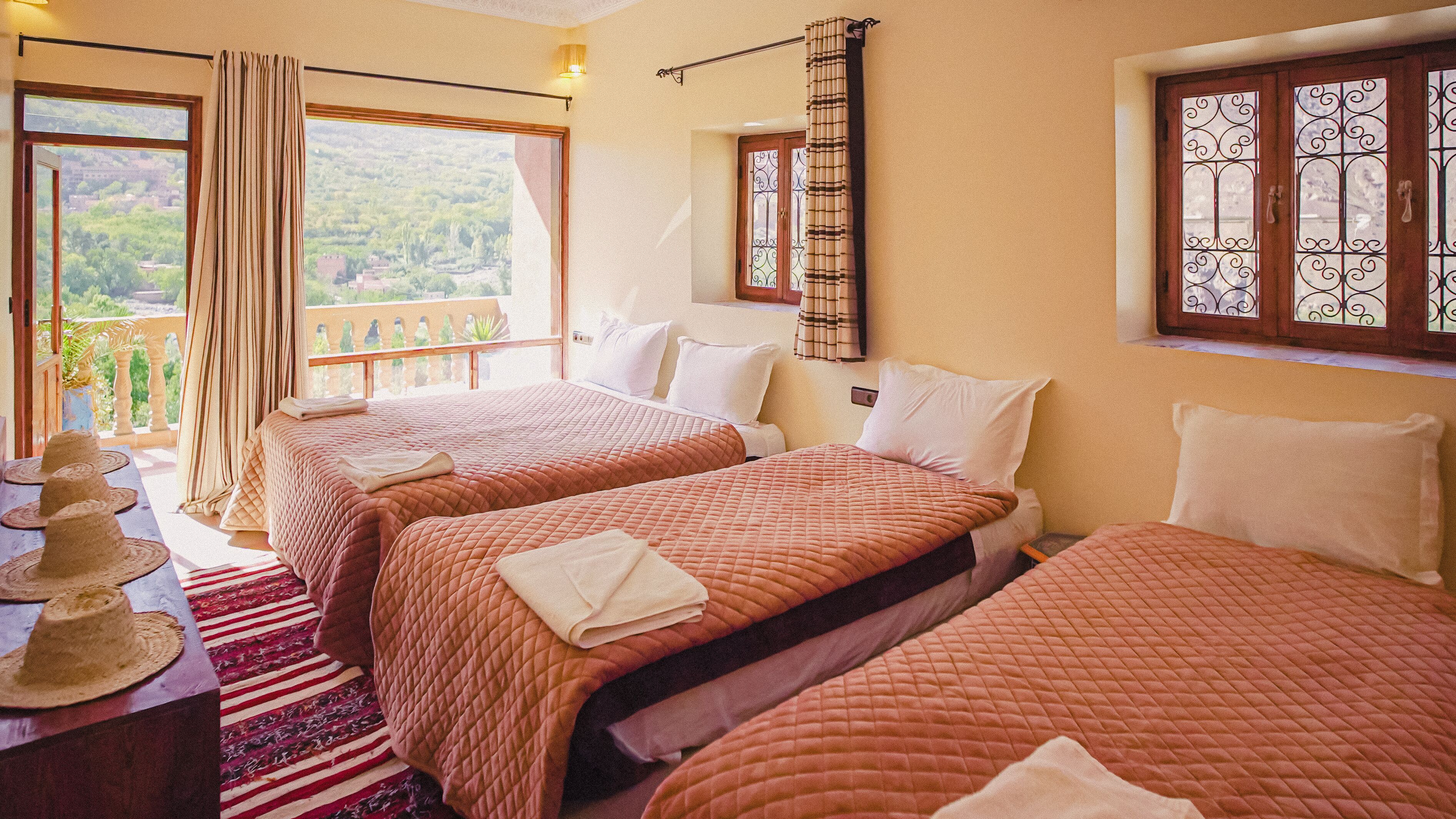 Habitación de hotel con dos camas, un balcón y vistas a zonas verdes.